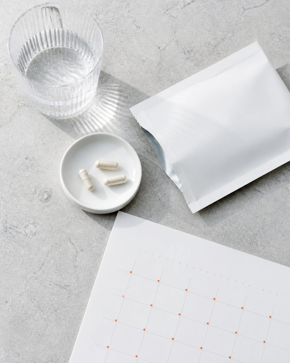 A daily supplement plan beside a glass of water