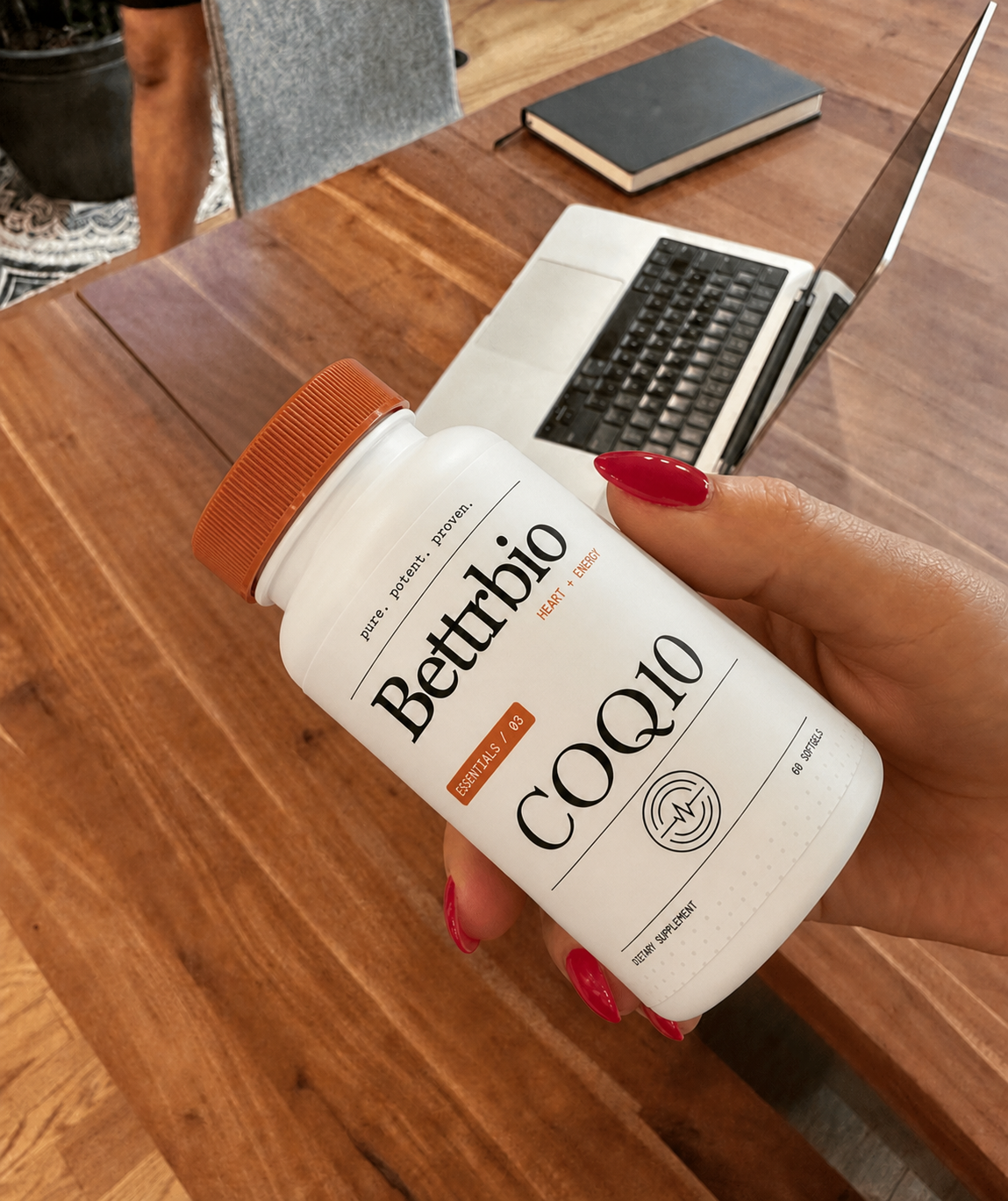 Customer holding Bettrbio CoQ10 beside a laptop